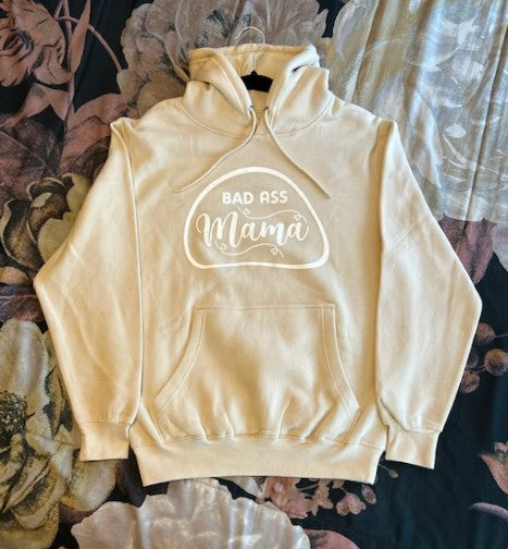 Release your Bad Ass Mama side with our cream hoodie, featuring a bold design that's perfect for fierce women. For the fearless and confident women who aren't afraid to show off their attitude, the Bad Ass Mama Cream Hoodie is a must-have wardrobe essential. The high-quality direct-to-garment design showcases bold font letters spelling out "Bad Ass Mama" against a cream-colored background that will make you stand out from the crowd.