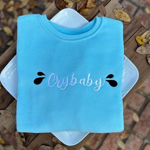 Our "Crybaby" sweatshirt for women is professionally embroidered featuring a soothing sky blue fleece-lined crewneck sweatshirt with white cursive lettering and two black teardrops on each side. Postpartum Depression can be a frightening experience, and it's normal to feel like a "Crybaby" sometimes. After giving birth to my son, I cried constantly for weeks for no apparent reason. Needless to say, I just felt very sad.