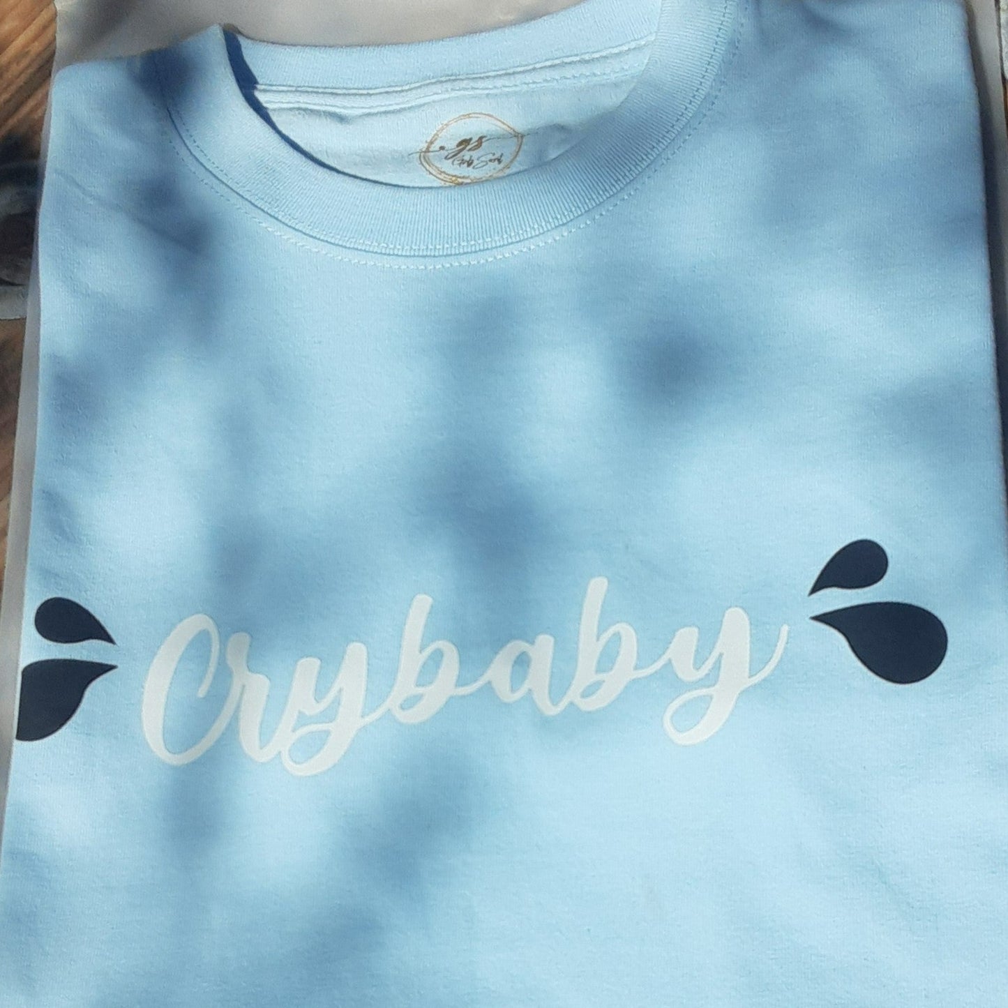 Our "Crybaby" t-Shirt for women is professionally screen printed featuring a soothing sky blue shirt with white cursive lettering and two black teardrops on each side. Postpartum Depression can be a frightening experience, and you can face multiple emotions at the same time. After giving birth to my son, I cried constantly for weeks for no apparent reason. Needless to say, I just felt very sad. I recall one occasion when my sister asked me if I was okay, and I immediately burst into tears.