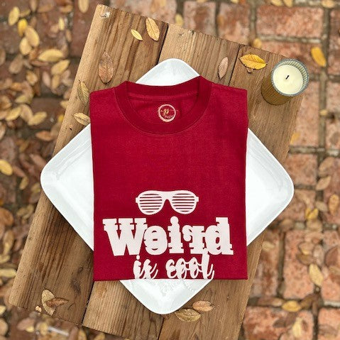 Our "Weird is Cool" women's t-shirt is professionally screen printed featuring a wine-colored shirt with blurred light gray letters and a pair of sunglasses over top. I'll be honest, I love all things weird. Quite frankly, I can be a big weirdo myself sometimes. But when the daughter of a good friend was being called "weird" at school, it bothered me because being weird is what makes us special and different - and it's okay to be different, even cool!